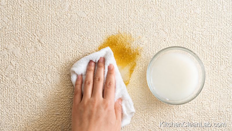 Hand blotting greasy stain on beige wallpaper with cornstarch water cloth